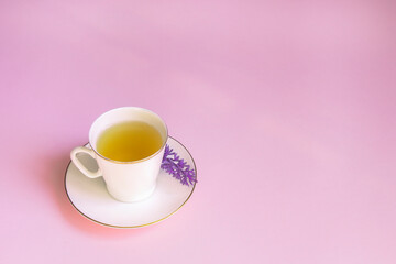 Ceramic Cup of green herbal tea on a pink surface. The view from the top. The concept of the tea party. Copy space. Template for recipes and ingredients.