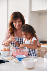 Obraz na płótnie Canvas Hispanic Grandmother And Granddaughter Having Fun In Kitchen At Making Cake Together