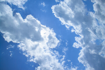 White fluffy clouds in a bright blue sky on a sunny day.