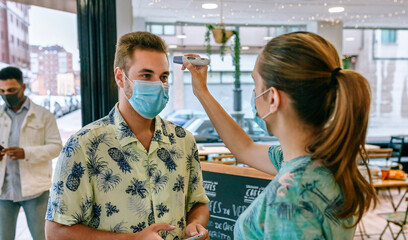 Coffee shop owner checking customers for fever upon entering