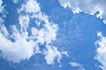 Obraz premium White fluffy clouds in a bright blue sky on a sunny day.