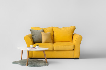 Stylish sofa and table on light background