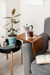 Cup of drink and coffee pot on armrest table in room