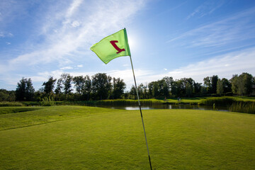 Obraz premium Green flag on a beautiful golf course by the ocean at sunset, sunrise.