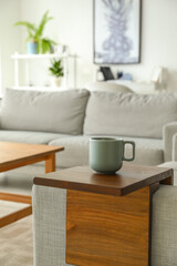 Cup of tea on armrest table in room