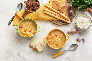 Pots of tasty rice soup on light background