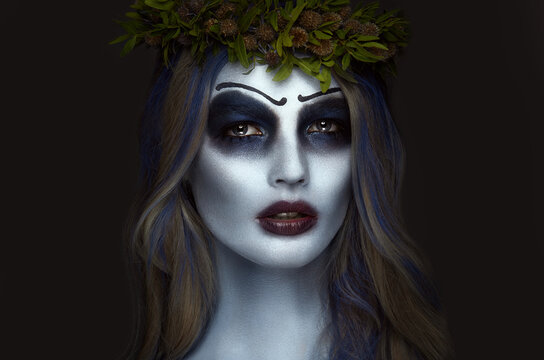 Portrait of a horrible scary Corpse Bride in wreath with dead flowers, halloween makeup