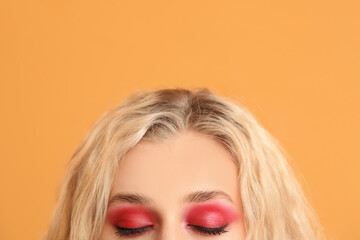 Young woman with beautiful eyeshadows on color background