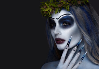 Portrait of a horrible scary Corpse Bride in wreath with dead flowers, halloween makeup and long...