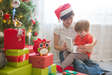 Obraz na płótnie Canvas Mother with her son decorating Christmas tree together, farm house design