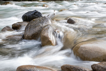 Steine schleifen fliessendes Wasser umspült mitten im Fluss,  lebendig
