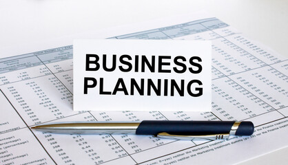 Text Business Planning on white card with blue metal pen on financial table