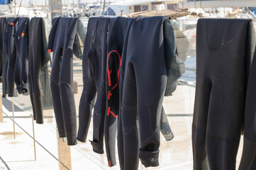 Fototapeta na wymiar Surf suits dry in the sun on a glass fence