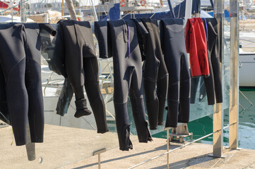 Surf suits dry in the sun on a glass fence