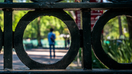 Rear view through metal gate of a man walking