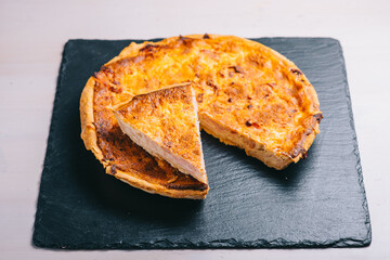 Traditional spanish cheese pie with bacon in that dark plate on the table.