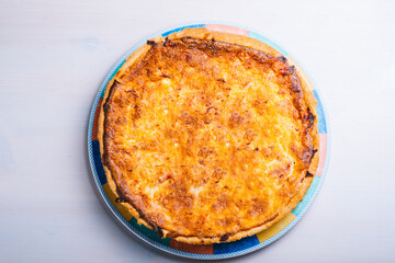 Traditional spanish cheese pie with bacon in a plate on the table. Top view