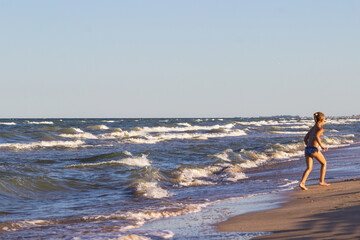 Fototapeta na wymiar Storm at sea. Child plays on beach near the water.