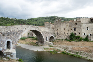 Fototapeta na wymiar The old historical architecture including the famous bridge across the small mountain river in medieval village Lagrasse, the most beautiful village of France. 