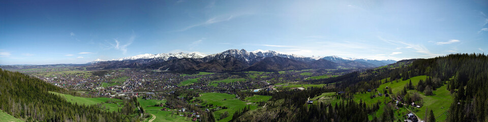 Fototapeta na wymiar Aerial panorama, view of mountains covered with snow in summer or spring. Giewont mountain massif in the Tatra Mountains and panorama of Zakopane, Poland, Europe. High resolution panoramic view.
