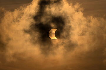 Obraz premium The Moon covering the Sun in a partial eclipse with dramatic cloud. Scientific background, astronomical phenomenon.