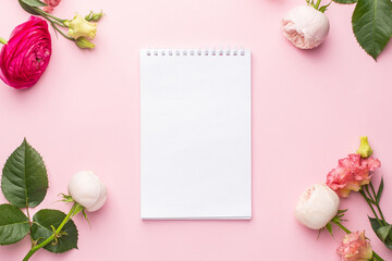 Notebook and pink flower bouquet on pink background