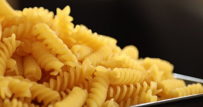 Heap of rotating fusilli pasta on plate closeup