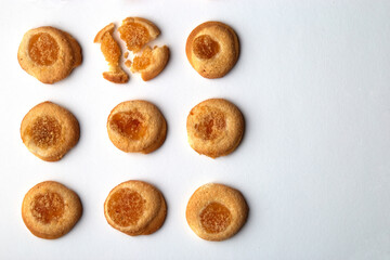 Nine handmade cookies with apricot jam arranged in even rows with free space for text. One in the top row is broken. on white background