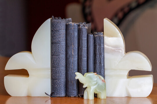 Old Books (bibles And Prayer Books) Between Onyx Bookends With An Elephant.