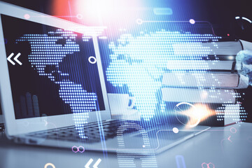 Double exposure of desktop with computer and world map hologram. International data network concept.