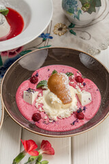 raspberry soup with ice cream and cookie on brown plate on the table at restaurant