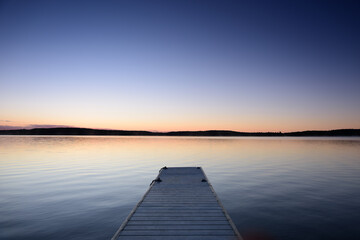 Small boat pier in cottage country. Calm lake with clear sky.