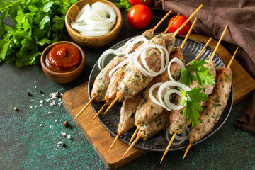 Turkish kebab. Homemade Kofta kebabs on a skewer with vegetables and sauce on a stone or slate background. Copy space.