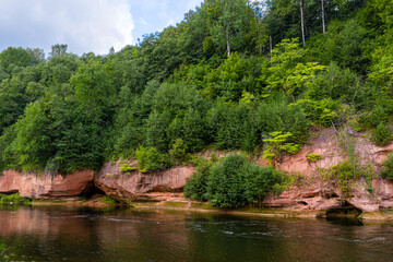 Fototapeta na wymiar landscape with sandstone cliffs on the river bank, fast flowing and clear river water, Kuku cliffs, Gauja river, Latvia