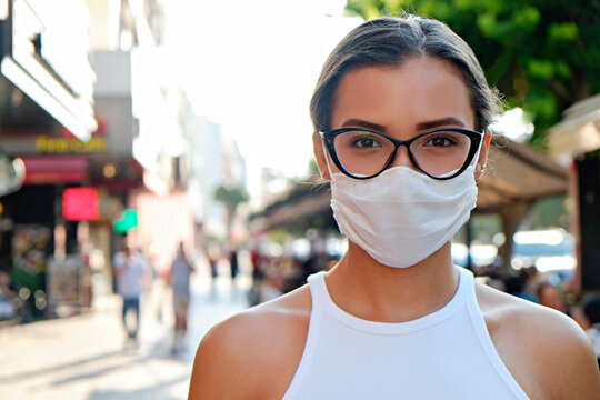 Portrait of young beautiful woman of Arabic ethnicity wearing disposable face mask as barrier to protect against contact with infectious materials at the streets. Close up, copy space, background.