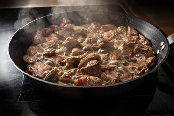 Sizzling and steaming beef in a frying pan for goulash or stew, cooking at home concept, selected focus