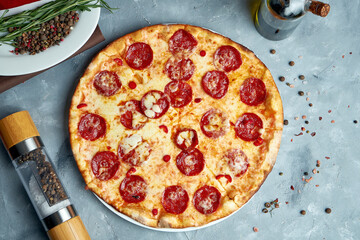 Pizza baked in a wood oven with melted cheese and chorizo salami on a gray background in a composition with cooking ingredients. Top view, food flat lay
