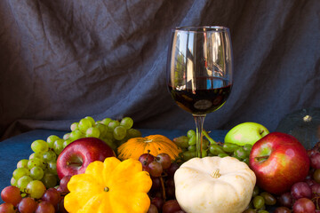 Full red wine glass and autumn and fall harvest, pumpkin, apple and grape