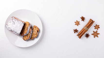 Traditional Christmas stollen cake on white background. Fruit bread with nuts, spices and dried fruit. Top view. Copy space.