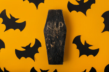 A Halloween yellow background with many bats and black and red coffin in the center. Festive flat...