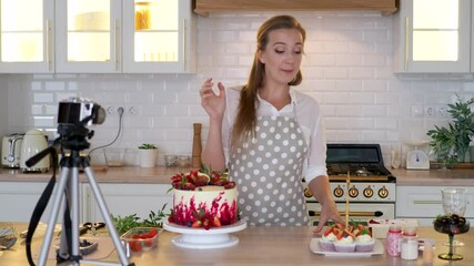 Blogger pastry chef makes a video lesson about cooking a cake. young woman in an apron at home in the kitchen tells the recipe on camera. Online broadcast, author leads a blog or course about cooking