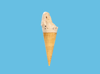 milk tea flavor ice cream cone with couple of bites on a blue background horizontal composition
