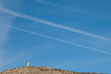 Observation tower and contrails of airplanes in the sky. Santa Eulalia La Mayor. Guara mountains....