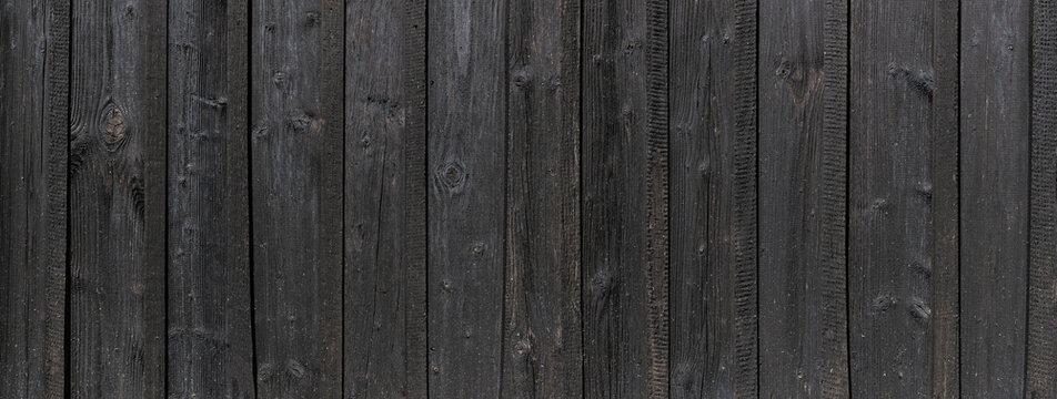 Panorama Detail der alten schwarzen Holzwand einer Scheune aus vertikalen Brettern mit leichten hellen Flusen