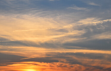 Naklejka na ściany i meble Orange fluffy sunset clouds over blue sky