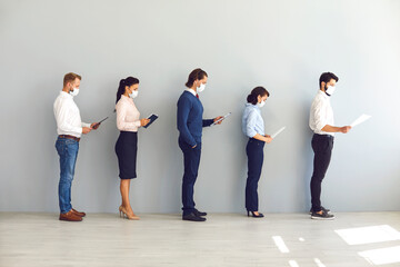 Group of business people in masks standing with documents in line and keeping distance in office