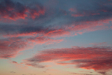 Naklejka premium Red fluffy sunset clouds over blue sky