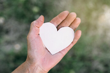 Fototapeta premium Grandma's hand holds a heart. The concept of protecting the elderly, retirement