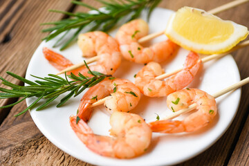 Salad grilled shrimp skewers delicious seasoning spices on white plate - appetizing cooked shrimps baked prawns , Seafood shelfish with rosemary and lemon