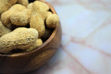 Close up, peanuts, group in wooden bowl on marble, space for text
